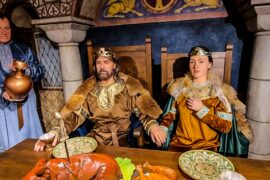 Doi monarhi cu coroane și robe bogate, subliniind importanța evenimentului.