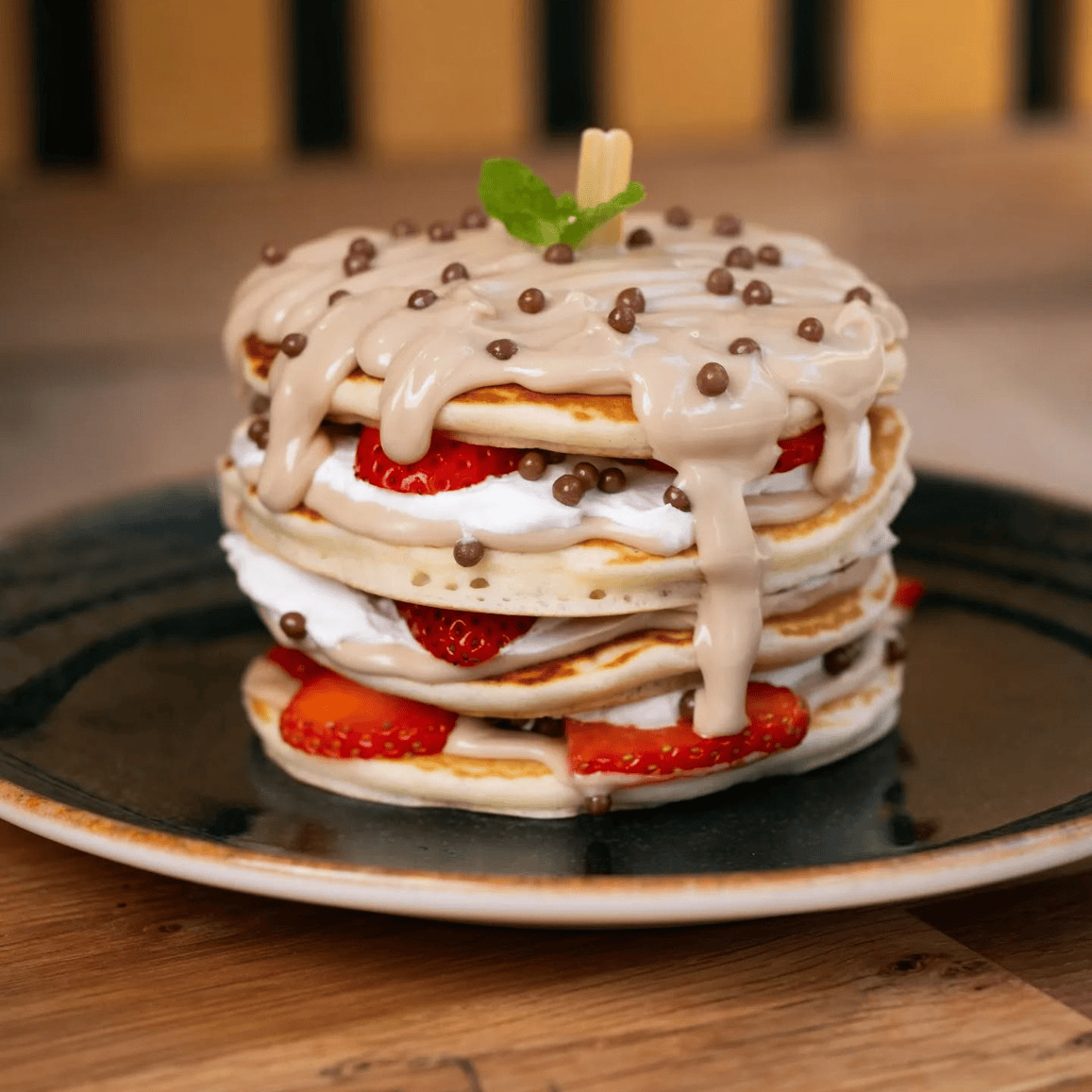 Strawberry Pancakes - A tall bowl of pancakes with strawberries and cream, garnished with mint.